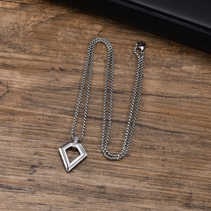 Detailed view of silver geometric diamond pendant with sleek box chain on wood surface