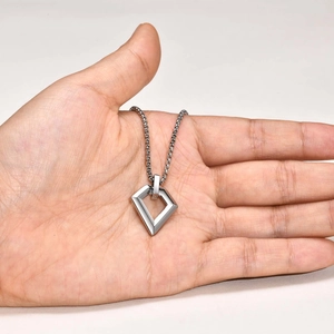 Close-up of geometric hollow diamond pendant with steel box chain held by hand