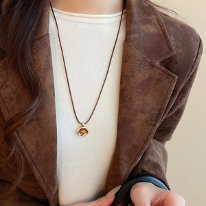 Close-up of vintage brown tiger eye stone pendant necklace on a white knit sweater