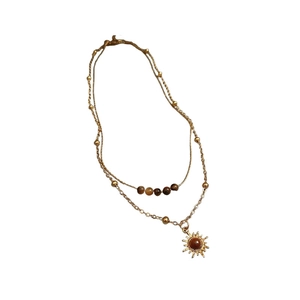 Vintage gold layered necklace with sun pendant and tiger eye stone beads on white background