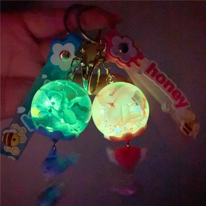 Close-up of luminous keychain spheres with flowers and honey straps in the dark