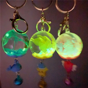 Luminous keychain featuring whale and heart charms glowing in blue yellow and red light
