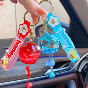 Detail of creative blue and red liquid keychains with glitter, bee strap and small bell