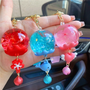 Close-up of assorted glowing jellyfish liquid keychains with glitters and dried flowers