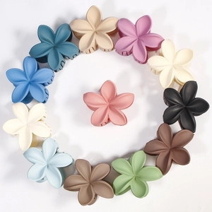 Macro view of multi-colored matte frangipani flower hair claws in a circular layout