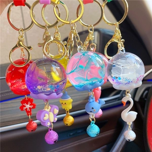 Detail of five assorted luminous dry flower keychains with swan and whale charms and bells