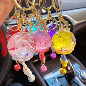 Close-up of dried flower bell keychains with glitter and swan charms in hand