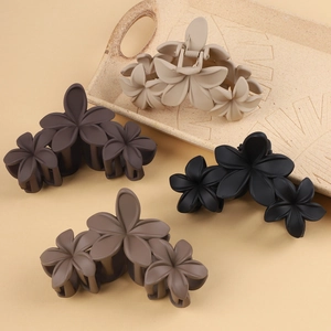 Detailed view of large matte plumeria flower hair claws in earthy neutral tones