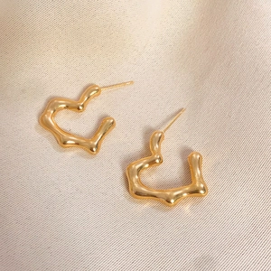 Irregular liquid metal heart stud earrings in gold finish on silk background