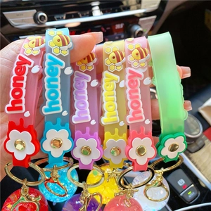Close-up of colorful liquid glitter keychains with silicone honey straps and bee charms