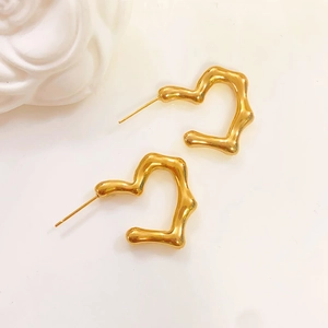 Detailed view of fluid metal gold heart earrings with irregular wavy texture