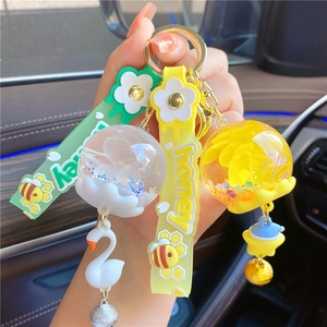Close-up of glowing floral resin keychain with white swan and honey silicone strap