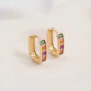Macro detail of 14K gold huggie earrings with rainbow zircon stones and inner hollow grid