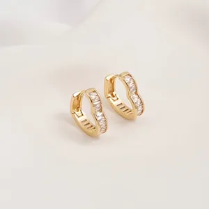 Detailed view of heart-shaped gold earrings set with rectangular cubic zirconia stones