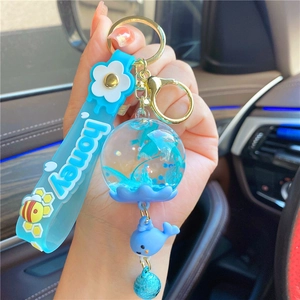 Detailed view of ocean theme keychain with blue whale charm and glitter liquid ball charm