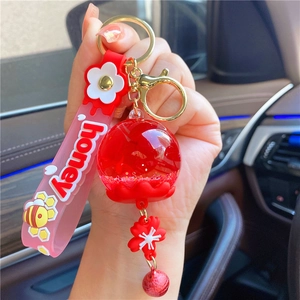 Close-up of a honey-themed red liquid keyring with glitter and a silicone honey strap