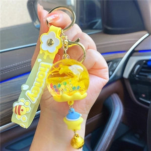 Close-up of yellow honey theme keychain with liquid glitter ball and bee hand strap