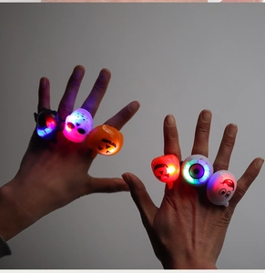 Close-up of hands wearing glowing Halloween LED rings with pumpkin and skull designs