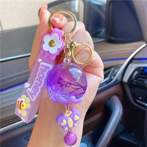 Detail of purple honey bee keychain with dried flower globe and butterfly charm