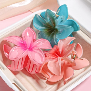 Detailed set of three translucent frangipani flower hair claws in pink, blue, and coral