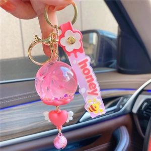 Close-up of pink liquid glitter keychain with heart pendant and honey silicone wristband