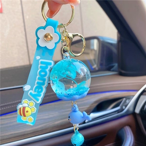 Detail of blue whale keychain with dried flower glass ball and honey silicone strap