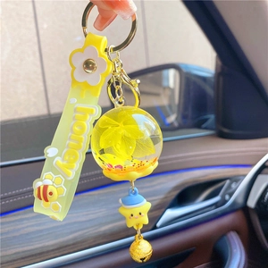 Close-up of yellow honey bee keychain with daisy strap and dried flower glass ball charm