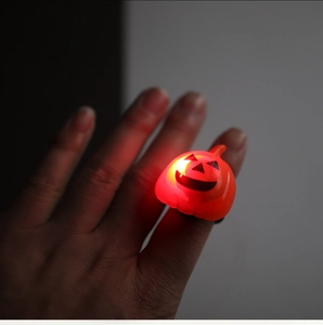 Close-up of a glowing LED pumpkin ring for Halloween with a Jack-o'-lantern face