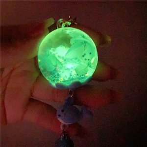 Glow in the dark whale keychain with dried flowers and blue fish pendant detail