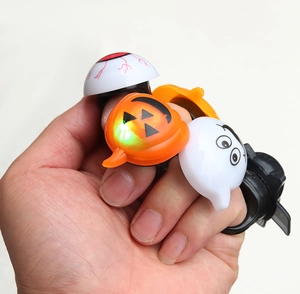Close-up of glowing Halloween rings featuring pumpkin, ghost, and eyeball designs on a hand