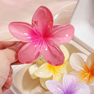 Detailed close-up of colorful translucent frangipani flower hair claws for women