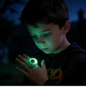 Boy wearing glowing green eyeball ring for Halloween night with spooky light effect