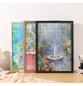 Three framed decorative puzzles in black, wood, and white frames on a cozy home desk