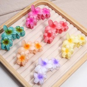 Macro shot of colorful resin frangipani flower hair claws with a matte gradient finish