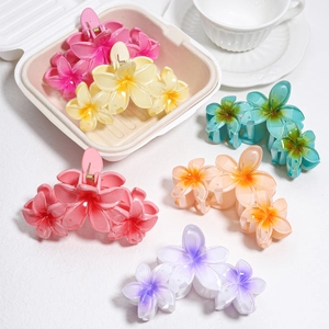 Detailed view of plumeria hair clips in assorted gradient colors on a white surface