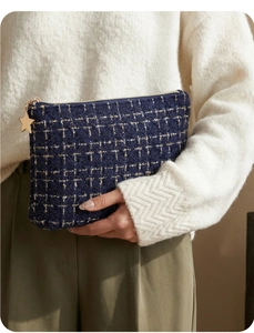 Detail of tweed navy blue cosmetic bag with golden star zipper puller and woven texture