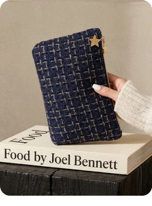 Detail showing deep blue tweed texture with gold thread and star-shaped zipper pull