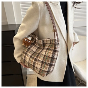 Model wearing a large vintage plaid canvas tote bag with a plush bear charm detail