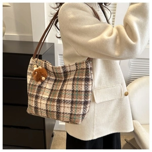 Side view of checkered canvas tote bag in beige and brown with plush charm detail