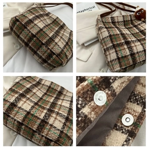 Macro detail of plaid tote bag showing tweed texture, magnetic clasp, and plush charm