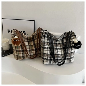 Close-up of canvas plaid tote bags with leather handles and decorative plush charms