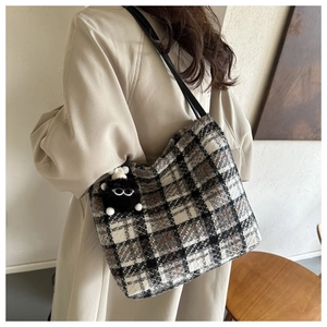 Close-up of black and white plaid canvas tote bag with a cute plush doll charm detail