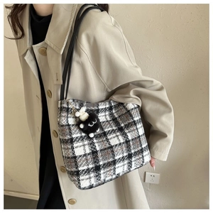 Detail of checkered canvas tote bag with black shoulder straps and a plush lamb pendant