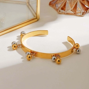 Polished gold and silver spheres on a geometric open bangle for a modern luxury look