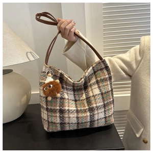 Detail of vintage plaid canvas tote bag with brown leather straps and furry monster charm