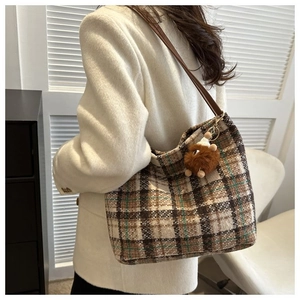 Detail of checkered canvas tote bag with leather straps and plush bear charm