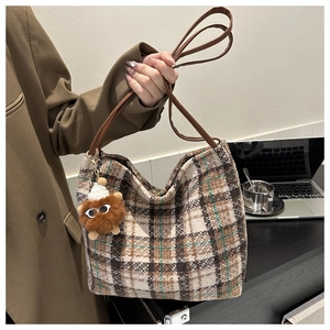 Detailed view of check pattern canvas tote bag with plush charm and leather strap