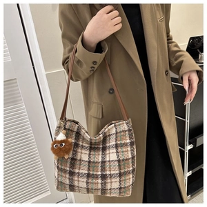 Close-up of retro plaid canvas tote bag with a cute plush monster charm detail