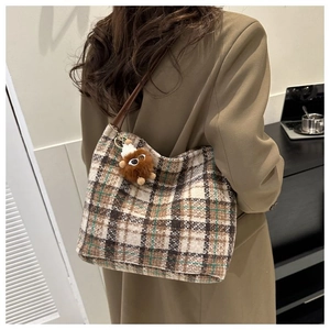 Detail of vintage plaid canvas tote bag with a cute brown plush monster pendant