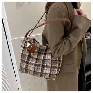 Detail of vintage plaid canvas tote bag with brown leather straps and plush charm